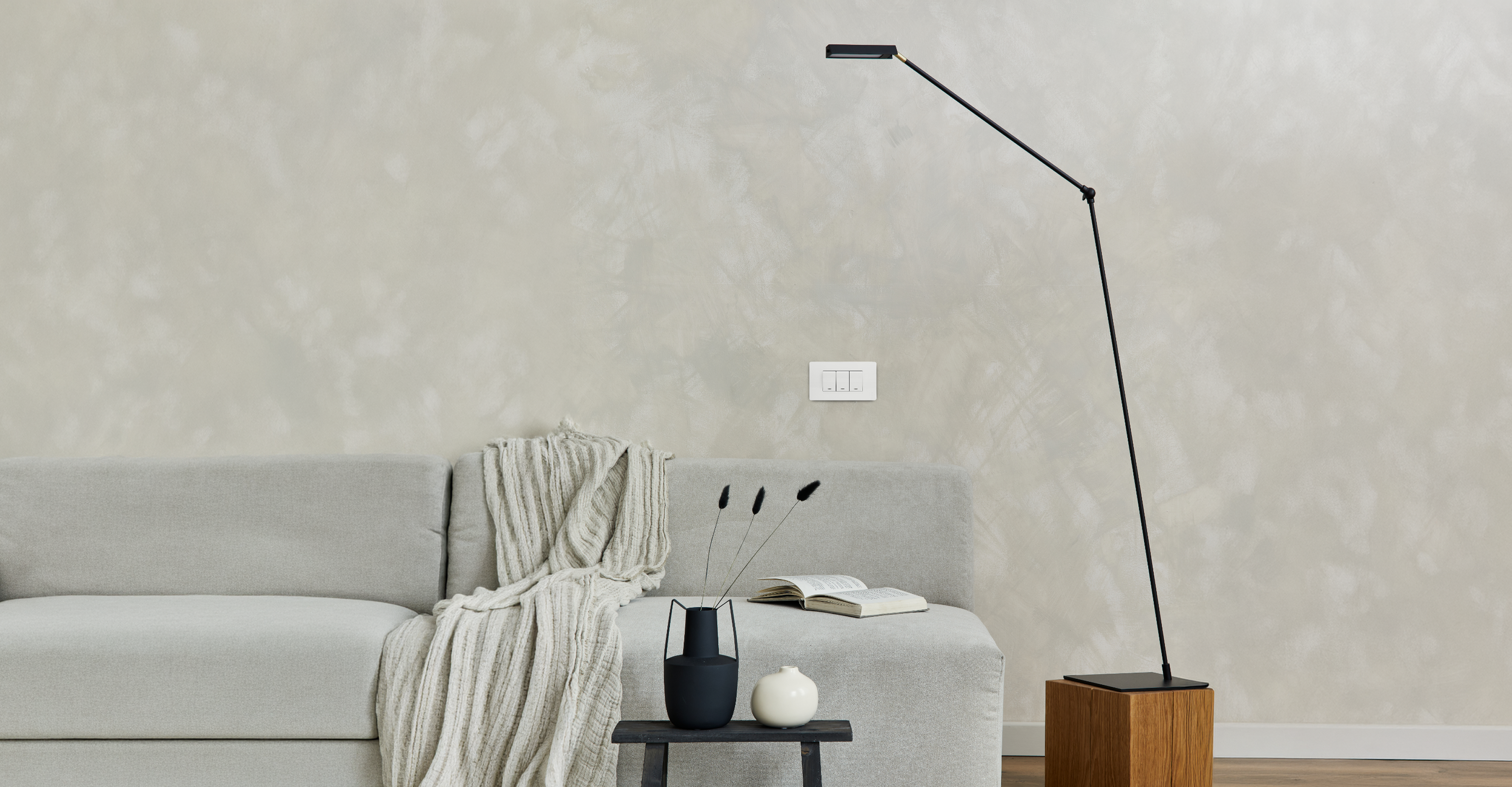 Grey wall sofa interior with black floor lamp and white wall switch